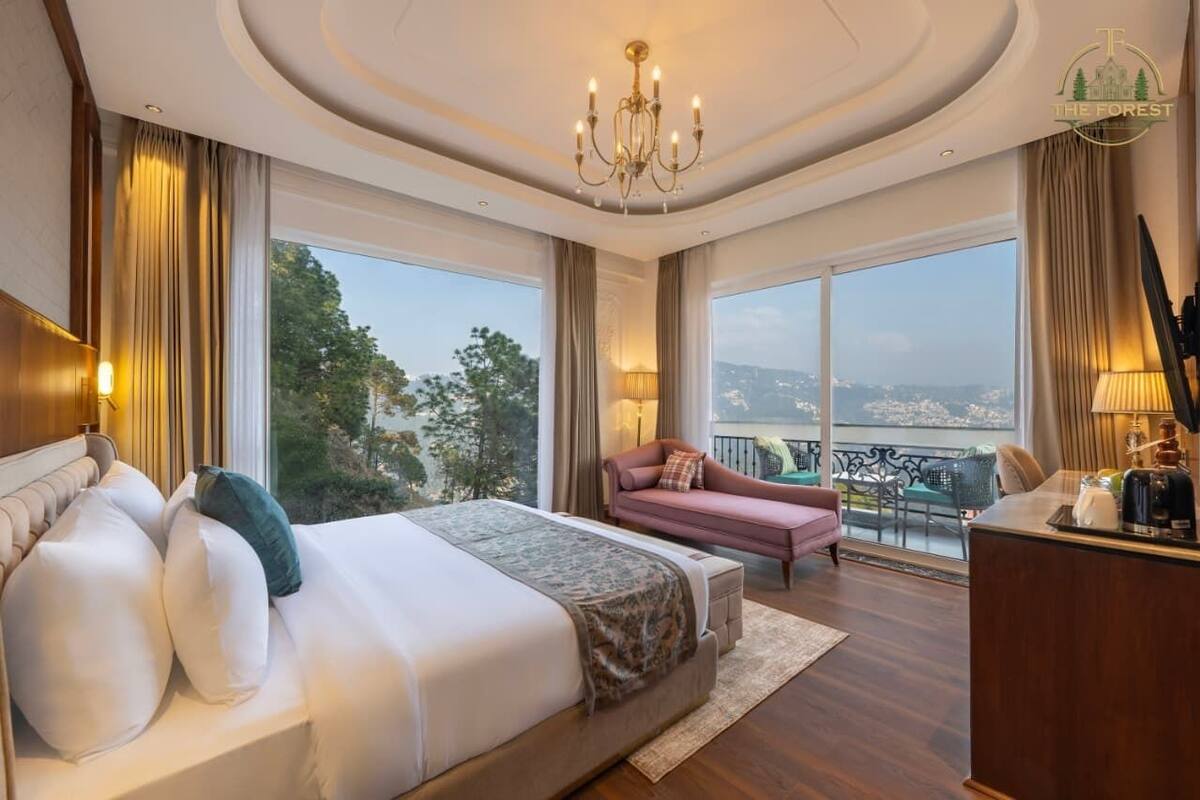 A spacious bedroom with a large bed, a sitting area, and a view of the city.