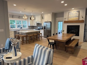A modern kitchen with a central island, wooden bar stools, a striped sofa, and a fireplace. - Amazing Lake views, semi private beach, private heated pool, hot tub & game room (South Haven)