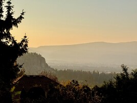 Un paisaje montañoso con un valle y una casa en primer plano.