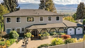 A two-story house with a garage, surrounded by a garden and trees. - The Susie Pearl Bed & Breakfast (Kelowna)