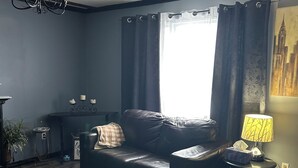 Un salón con un sofá azul oscuro, un tapete estampado, una mesita y una lámpara.