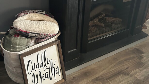 Una chimenea con un cartel que dice "Cuddle Weather".