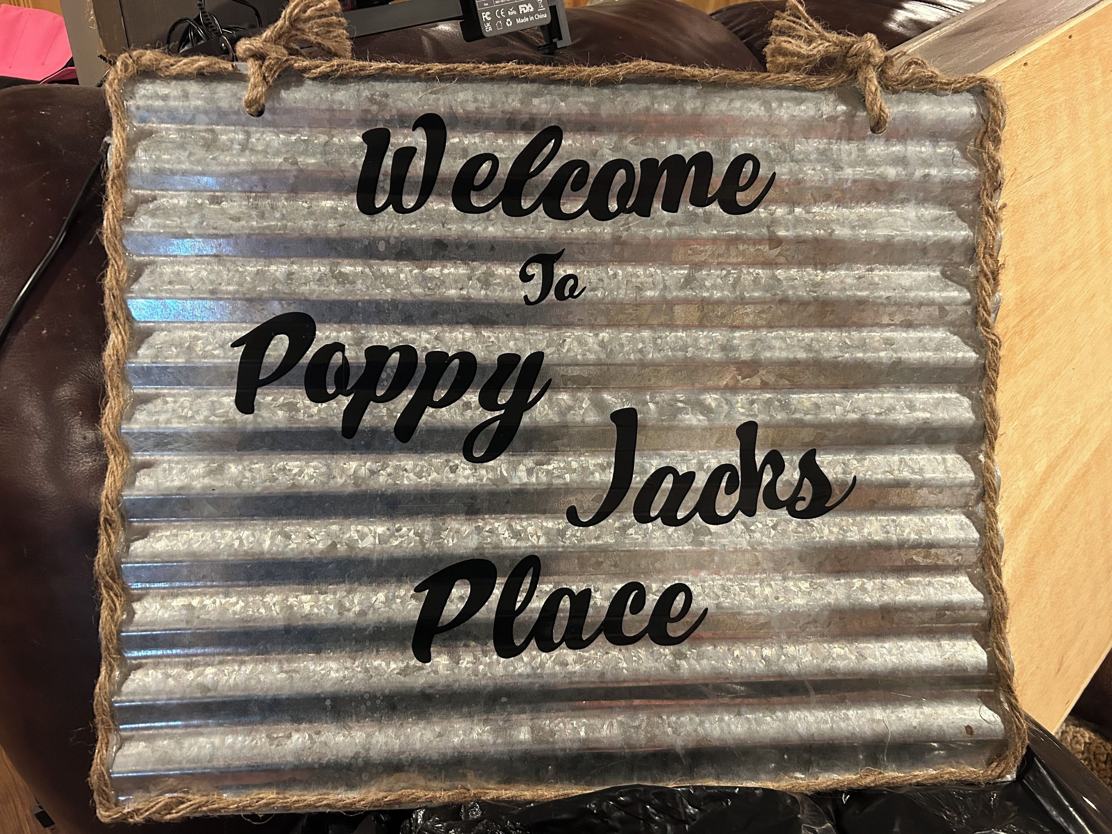 Une pancarte d’accueil avec l’inscription « Bienvenue chez Poppy Jacks » sur un fond en métal ondulé.