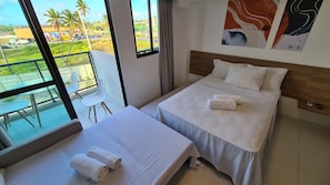 A hotel room with two beds, a balcony with a view of palm trees and a road, and a painting on the wall. - Mana Beach Experience By Aft (Ipojuca)