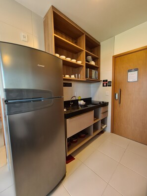 A kitchen with a stainless steel refrigerator, wooden shelves, a microwave, and a sink. - Mana Beach Experience By Aft (Ipojuca)