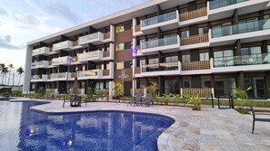 A multi-story hotel with a swimming pool, outdoor seating, and a sign reading "PONO". - Mana Beach Experience By Aft (Ipojuca)