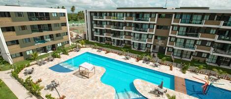 Un hôtel moderne doté d’une grande piscine, de nombreux balcons et d’un espace extérieur bien aménagé.