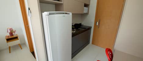 A compact kitchen with a refrigerator, microwave, and coffee maker on the countertop.