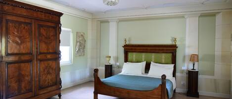 Un dormitorio con una cama grande de madera, un armario de madera y una araña.