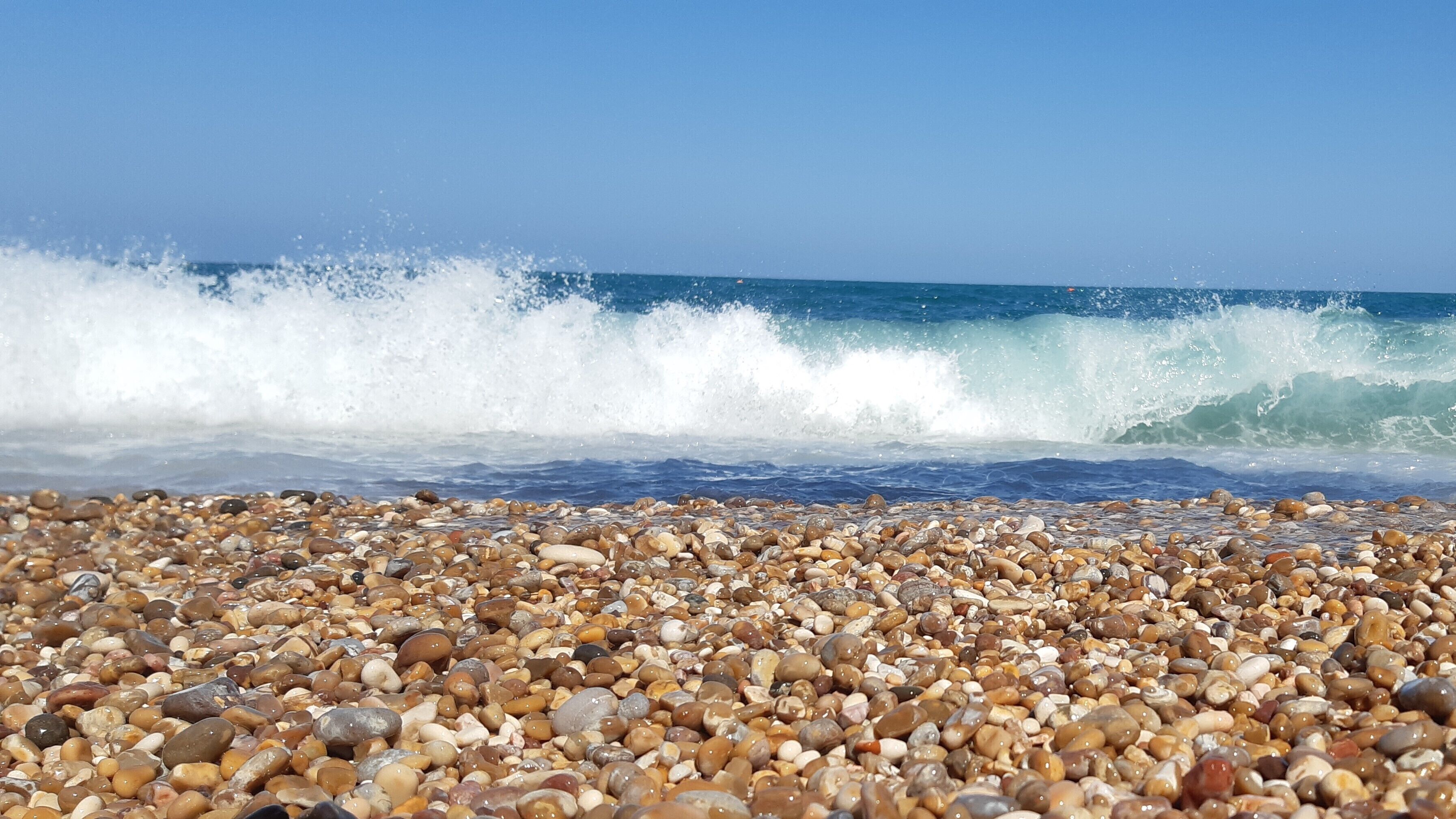 A pebbled beach with waves crashing onto the shore.