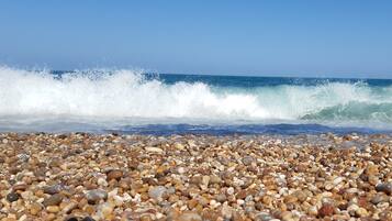 A pebbled beach with waves crashing onto the shore.