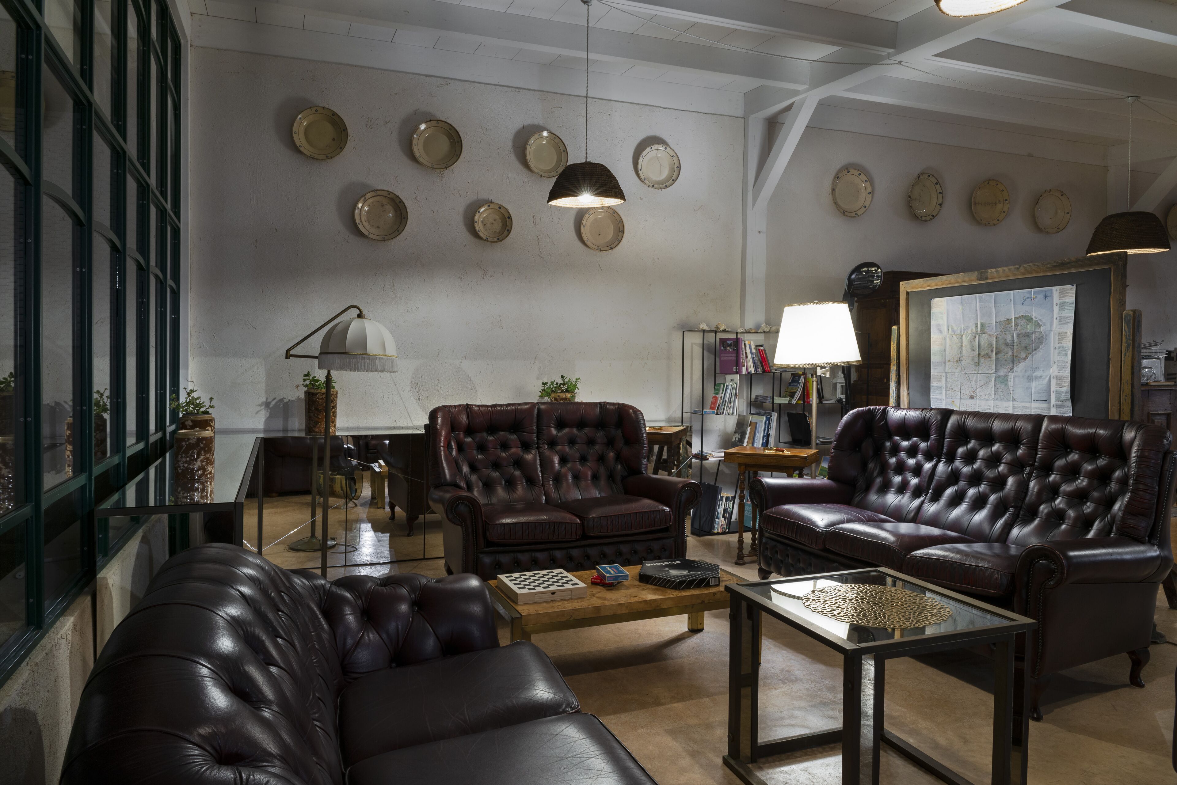 A spacious living room with leather sofas, a coffee table, and a bookshelf.