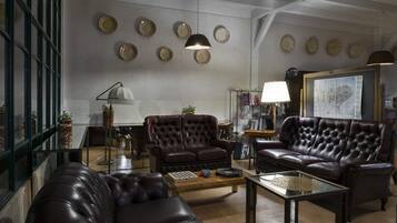 A spacious living room with leather sofas, a coffee table, and a bookshelf.