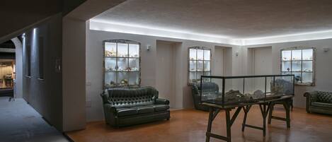 A spacious room with a large window, a glass display table, and a leather sofa.