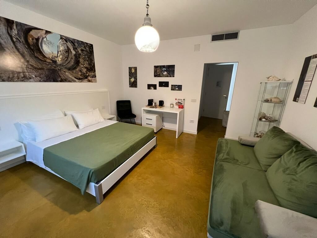 Ein Schlafzimmer mit einem Bett, einem Schreibtisch und einem grünen Sofa.