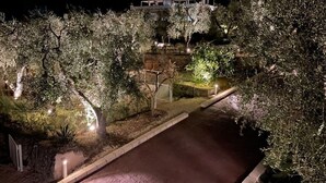 A nighttime view of a hillside property with a paved driveway leading to a building.