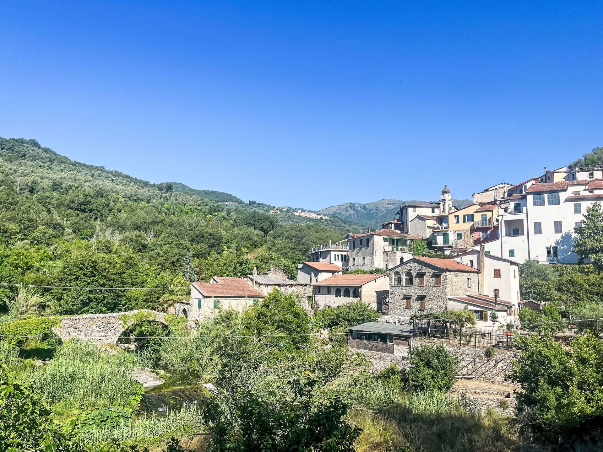 Un village perché sur une colline, avec des bâtiments en pierre, une église et une végétation luxuriante.