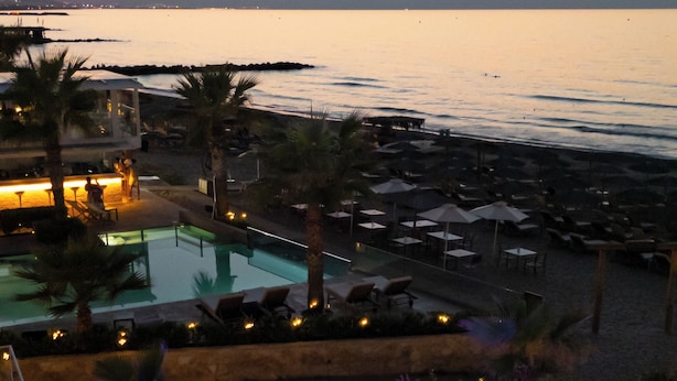 A resort with a pool area, lounge chairs, and a view of the ocean at sunset. - Vergina Beach Resort (Chania)