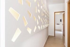 A hallway with a modern wall design featuring geometric cutouts and recessed lighting. - Vergina Beach Resort (Chania)