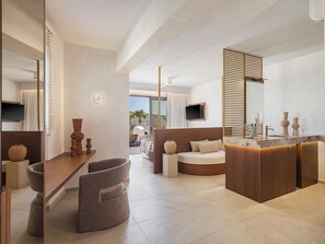 A modern hotel room with a large bed, a wooden vanity, and a seating area with a view of the ocean. - Vergina Beach Resort (Chania)