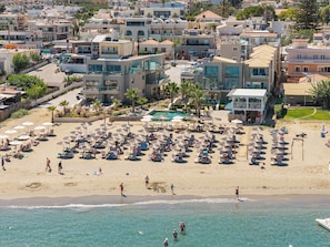A coastal hotel with multiple-story buildings, a beach with sun loungers and umbrellas, and a swimming pool. - Vergina Beach Resort (Chania)