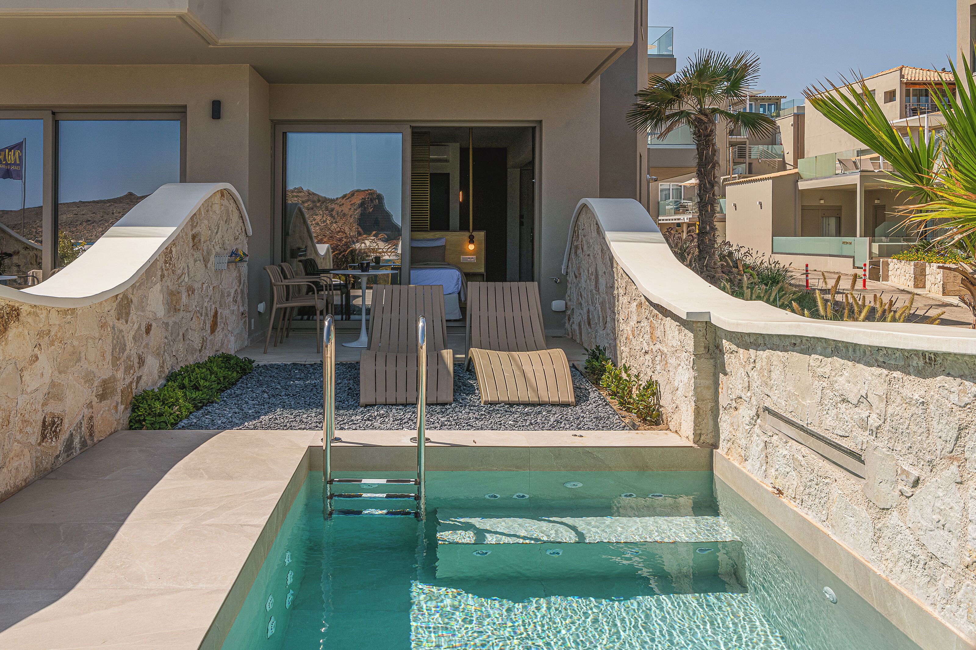 A pool area with lounge chairs, a table, and a view of the mountains.