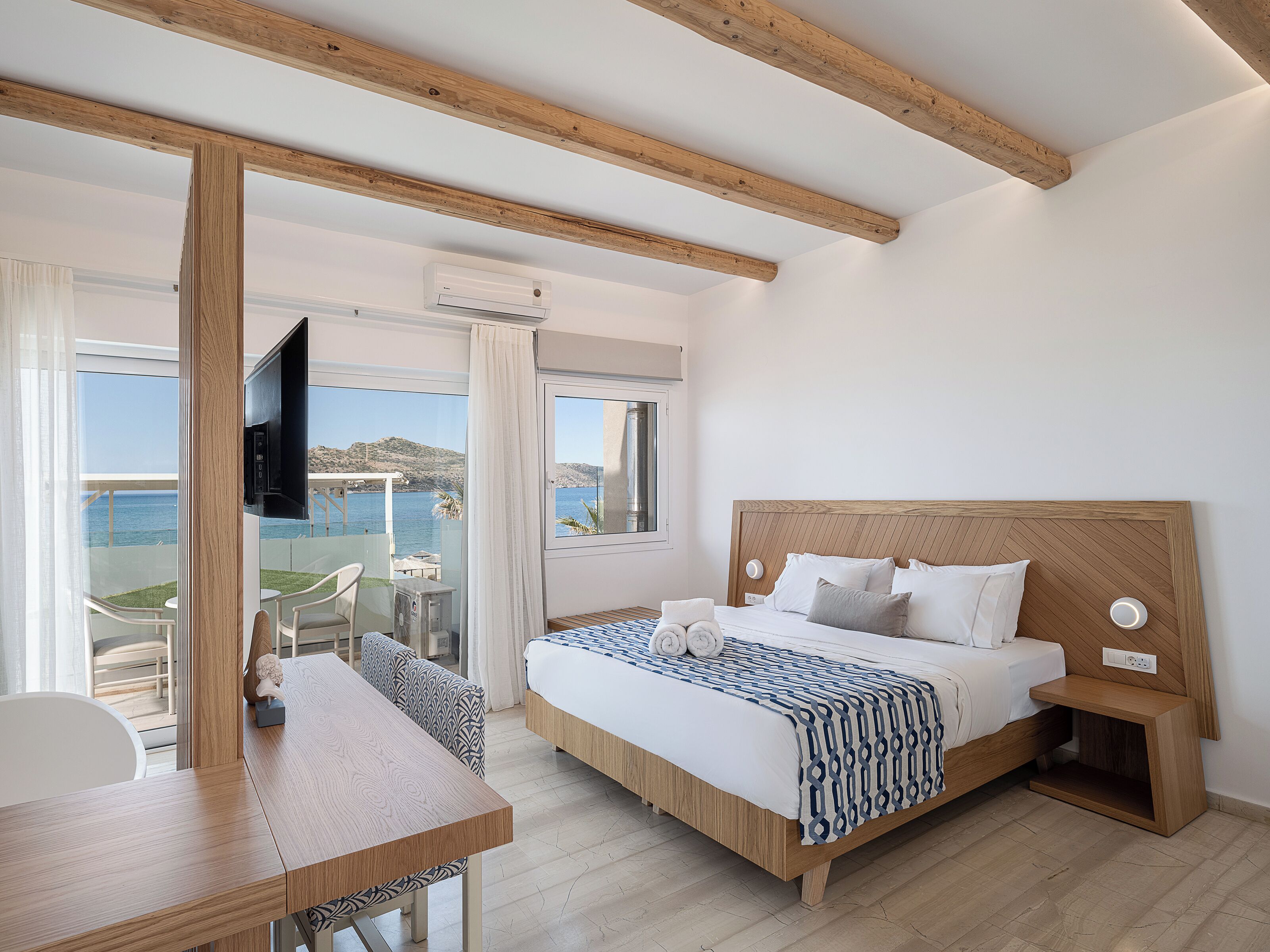 A bedroom with a bed, bedside table, and a view of the sea.