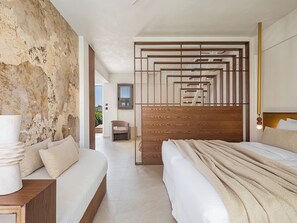 A modern bedroom with a large bed, a sofa, and a unique wooden partition. - Vergina Beach Resort (Chania)