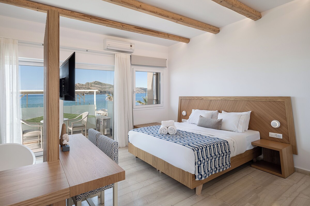 A bedroom with a bed, bedside table, and a view of the sea.