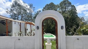 A white building with an arched entrance, a small statue, and a pool visible through the doorway. - Felysia Villa Iii (Kintamani)