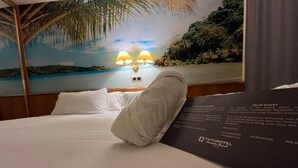 Une chambre d’hôtel avec un lit, une table de chevet avec des lampes et une fresque représentant une scène de plage.