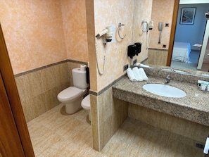 A bathroom with a toilet, a sink, and a mirror. - Futurotel Cambrils Paradise Resort (Vinyols i els Arcs)