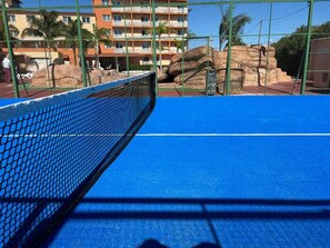 A tennis court with a net, surrounded by a green fence and palm trees. - Futurotel Cambrils Paradise Resort (Vinyols i els Arcs)
