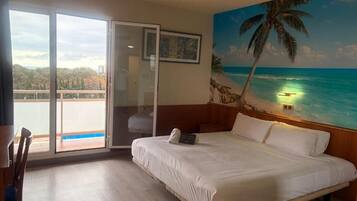 Een slaapkamer met een groot bed, uitzicht op de oceaan, een balkon en een schilderij van een strand.