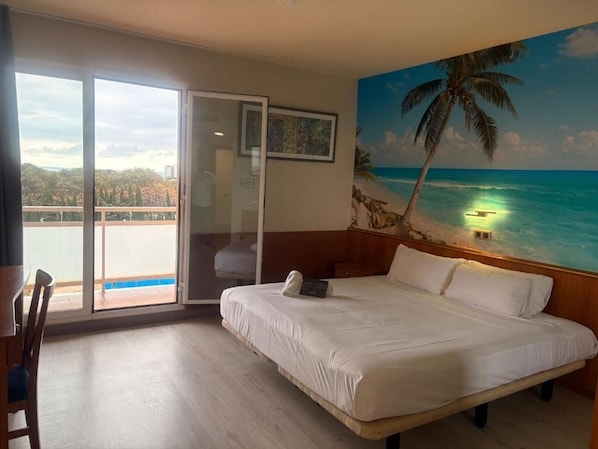 Un dormitorio con una cama grande, vista al océano, un balcón y un cuadro con una playa.