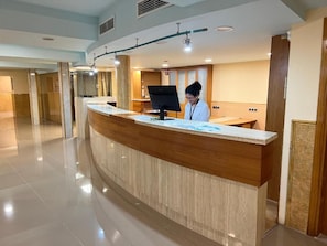 A reception desk with a digital screen, a counter, and a person standing behind it. - Futurotel Cambrils Paradise Resort (Vinyols i els Arcs)