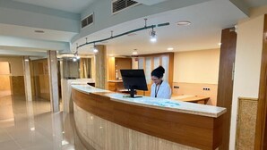 Un comptoir d’accueil doté d’un écran numérique, avec une personne derrière le comptoir.