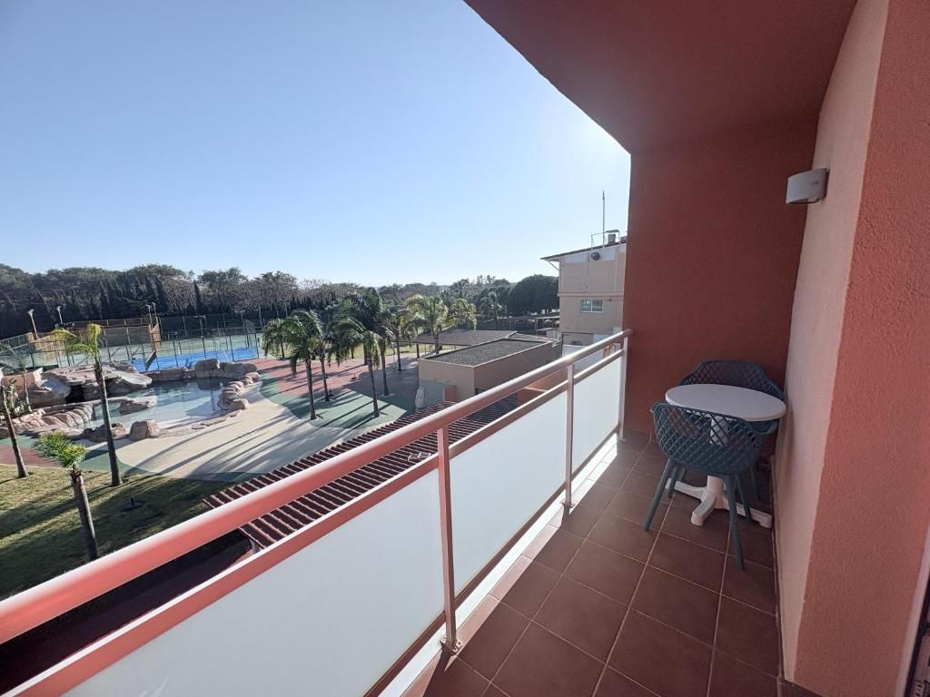 En balkon med udsigt over en swimmingpool og palmer.