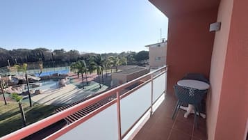 En balkon med udsigt over en swimmingpool og palmer.
