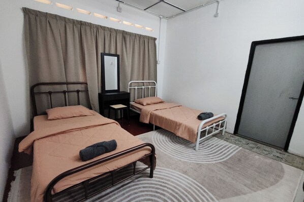 A bedroom with two single beds, a mirror, a desk, and a wardrobe.