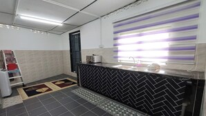 A bathroom with a black and white herringbone tile backsplash, a sink, a mirror, and a window with purple and white stripes. - DRH Villa (Ipoh)