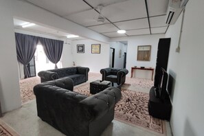 Un salon comprenant un canapé, une table basse, un téléviseur et un tapis à motifs.