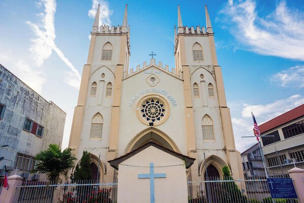 A church with a central dome and two towers, surrounded by a fence and palm trees. - Sleepy Nomad Hostel (Malacca City)