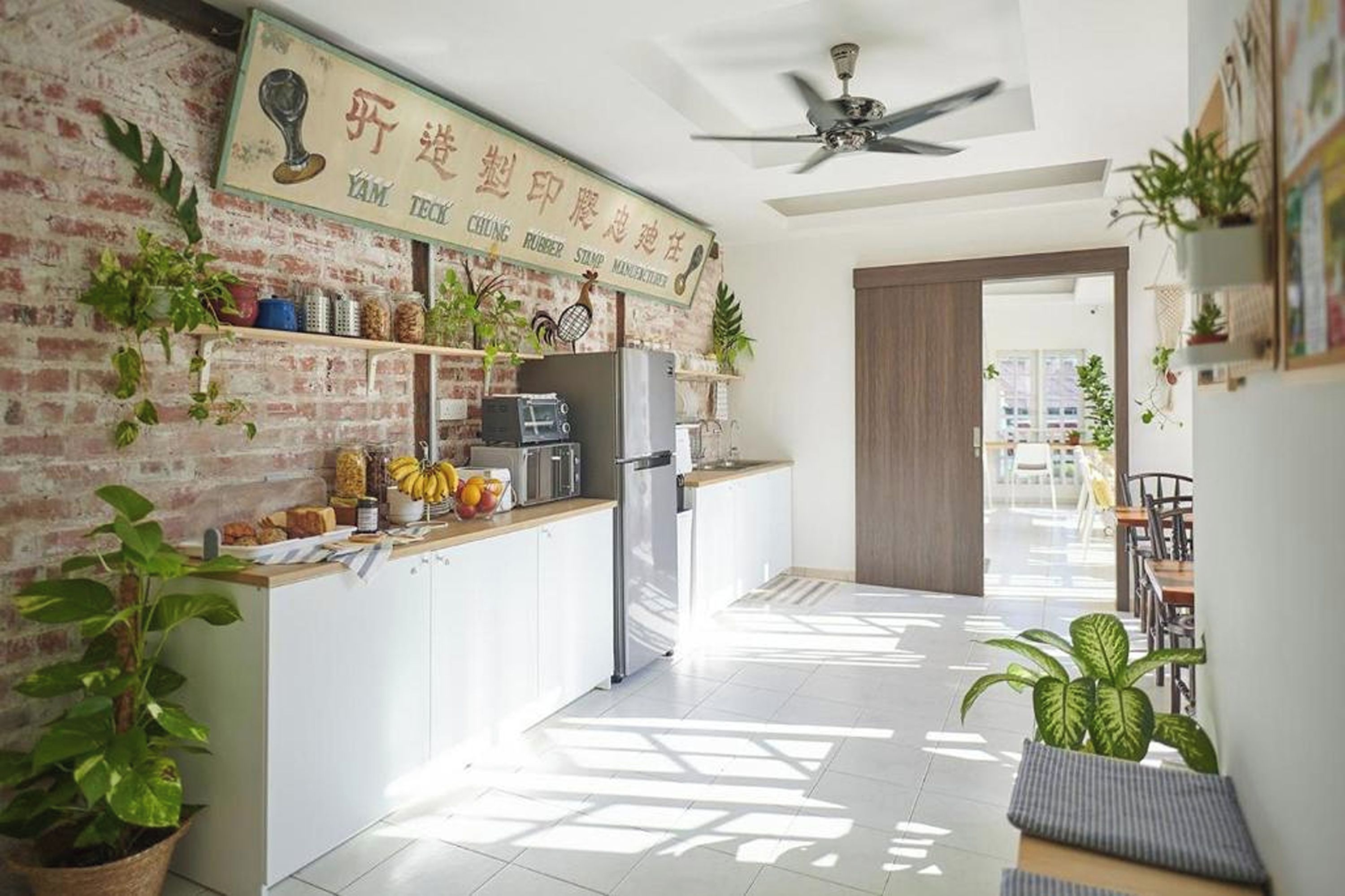 A modern kitchen with a brick wall, a ceiling fan, and a sign above the counter.
