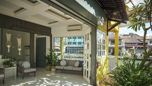 A modern outdoor lounge area with a sofa, chairs, and potted plants. - Sleepy Nomad Hostel (Malacca City)