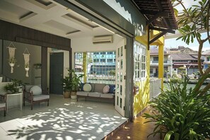 A modern outdoor lounge area with a sofa, chairs, and potted plants. - Sleepy Nomad Hostel (Malacca City)
