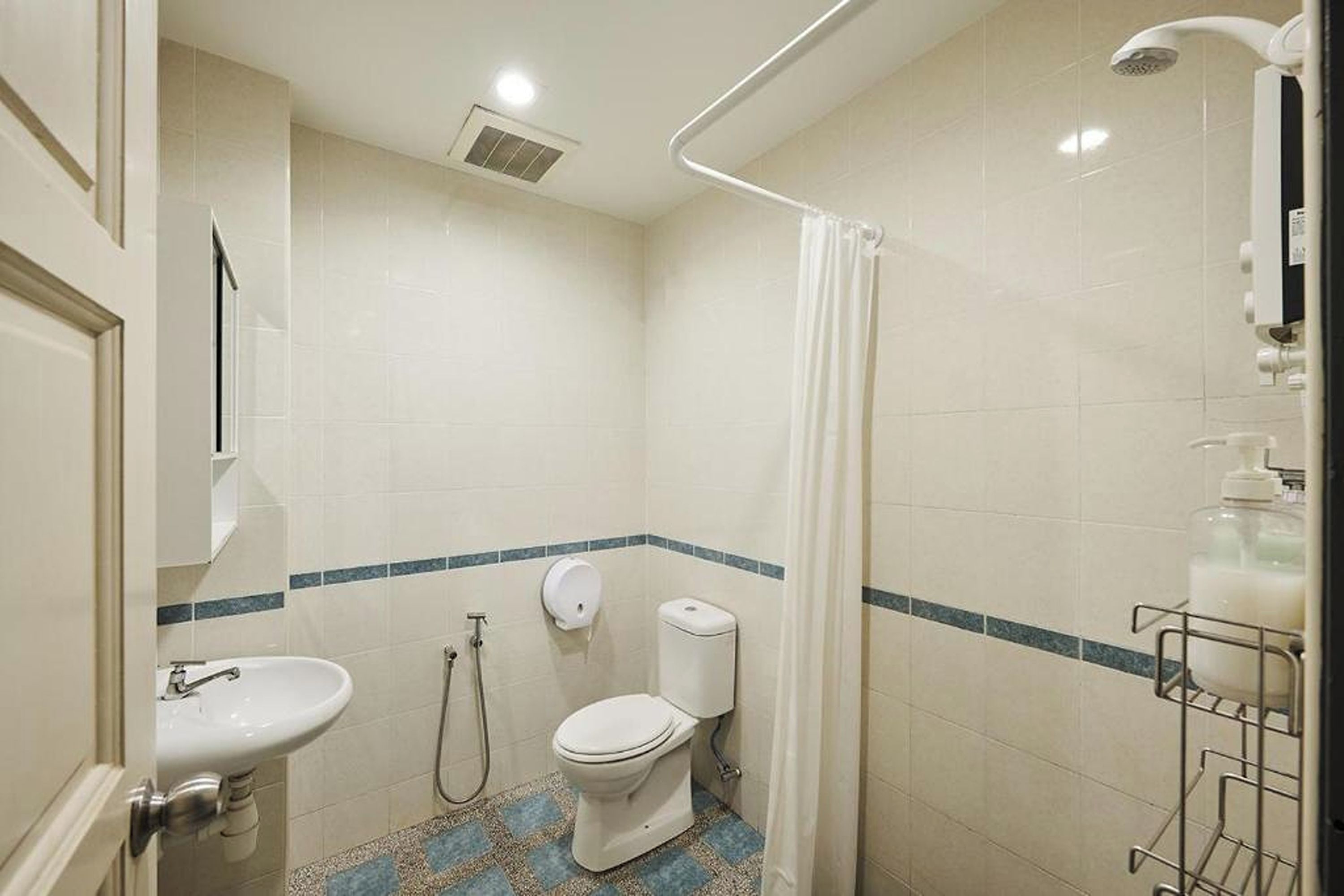 A bathroom with a toilet, sink, shower, and a hand dryer.