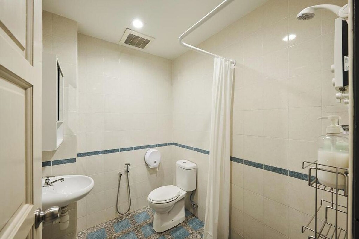 A bathroom with a toilet, sink, shower, and a hand dryer.