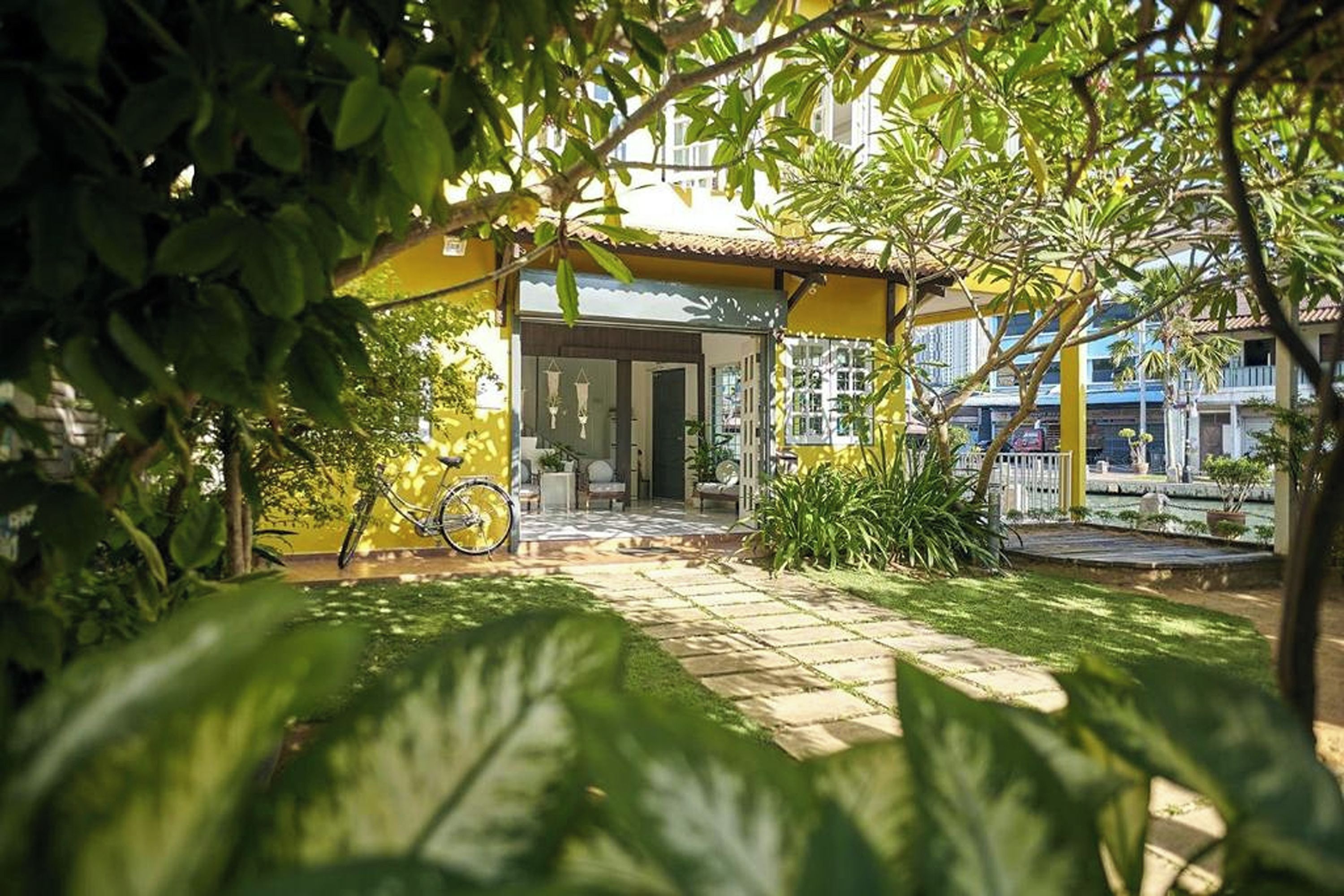 A courtyard with a yellow building, a bicycle, and potted plants.