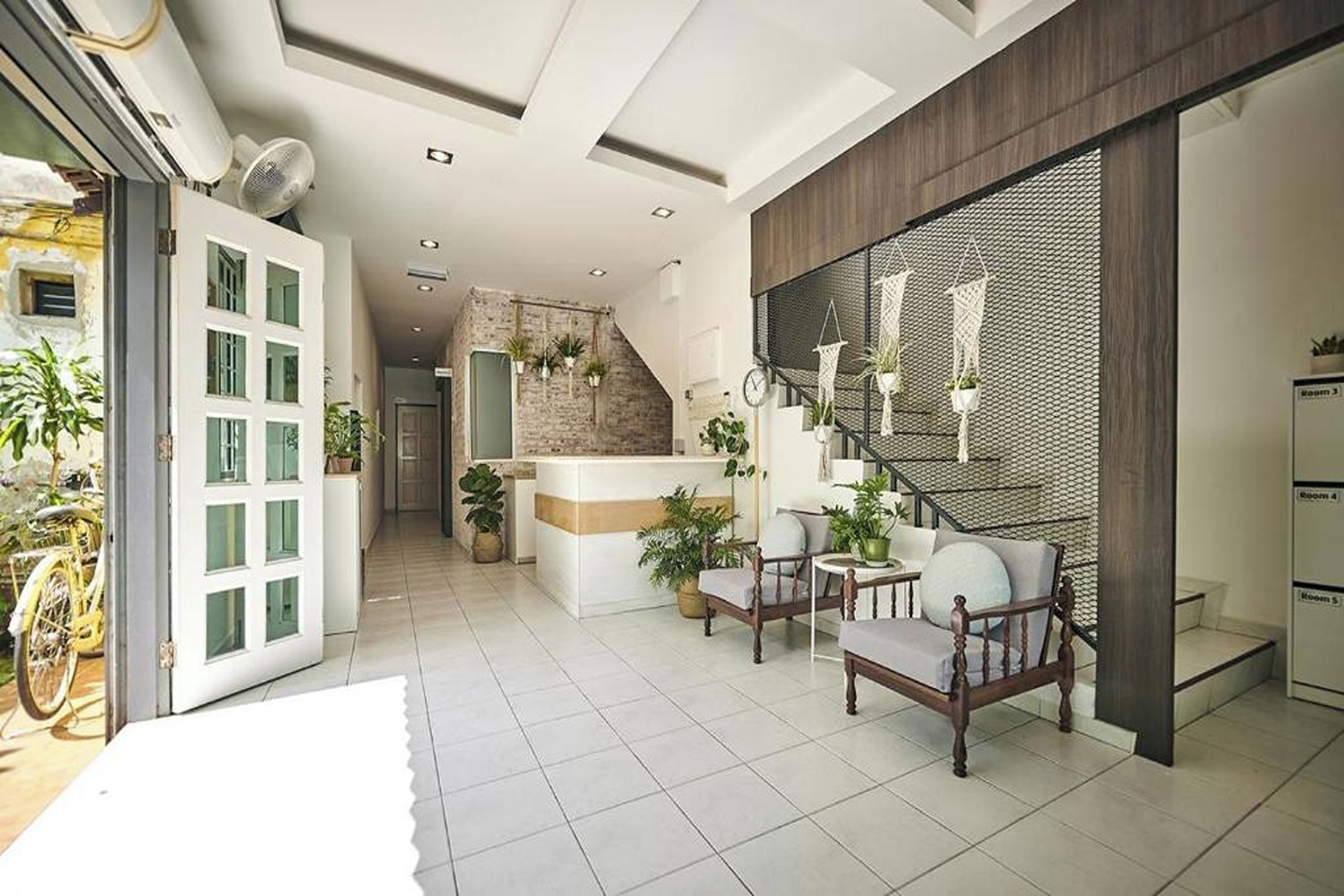 A modern interior with a reception desk, seating area, staircase, and a view of the outside.